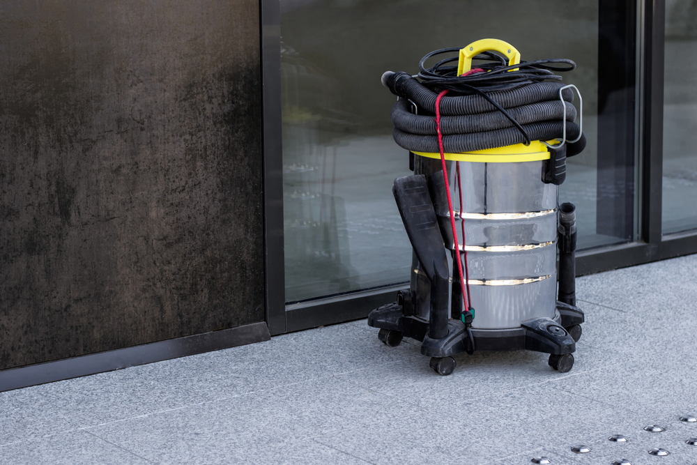 auto floor scrubber being pushed by a person on a tile floor