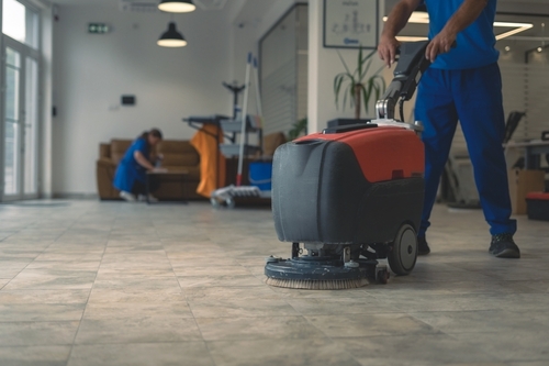 person with industrial cleaning equipment for scrubbing tile flooring