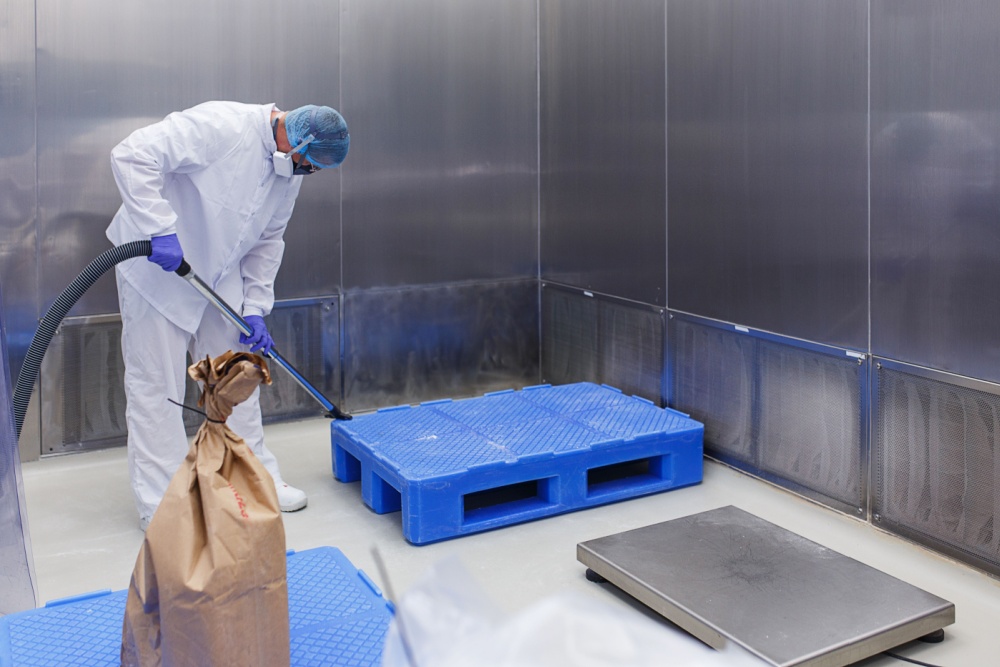 cleaner in protective clothing and a mask makes cleaning of a sterile room.