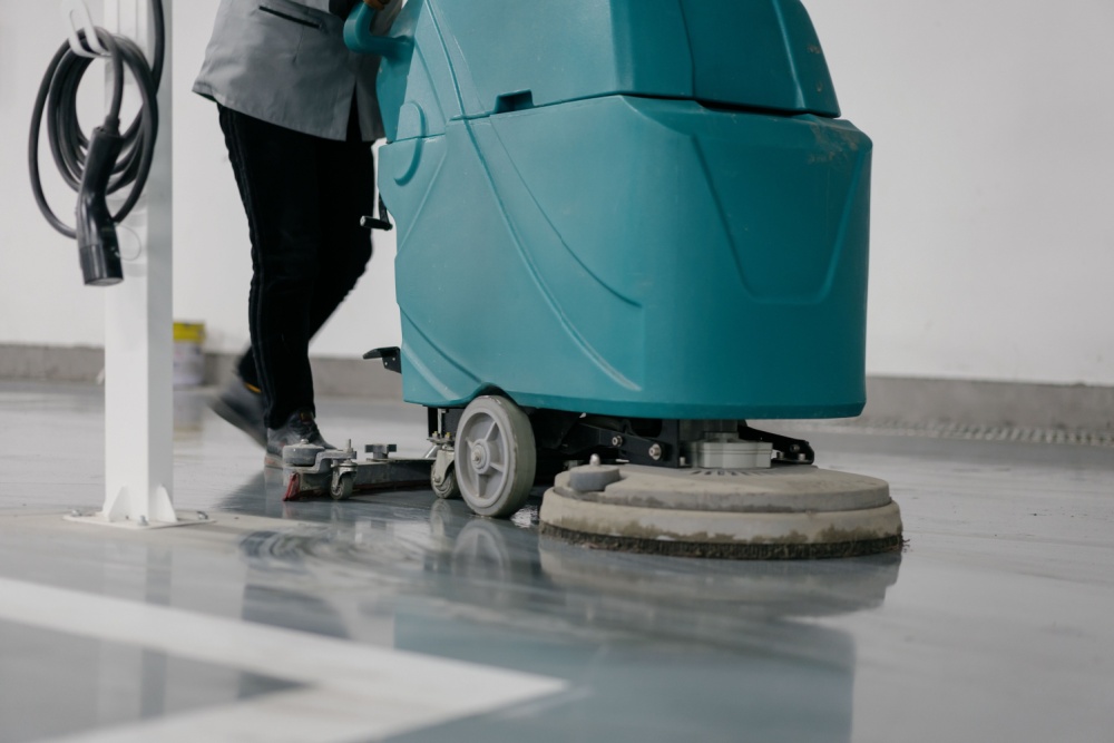worker is cleaning floor with machine
